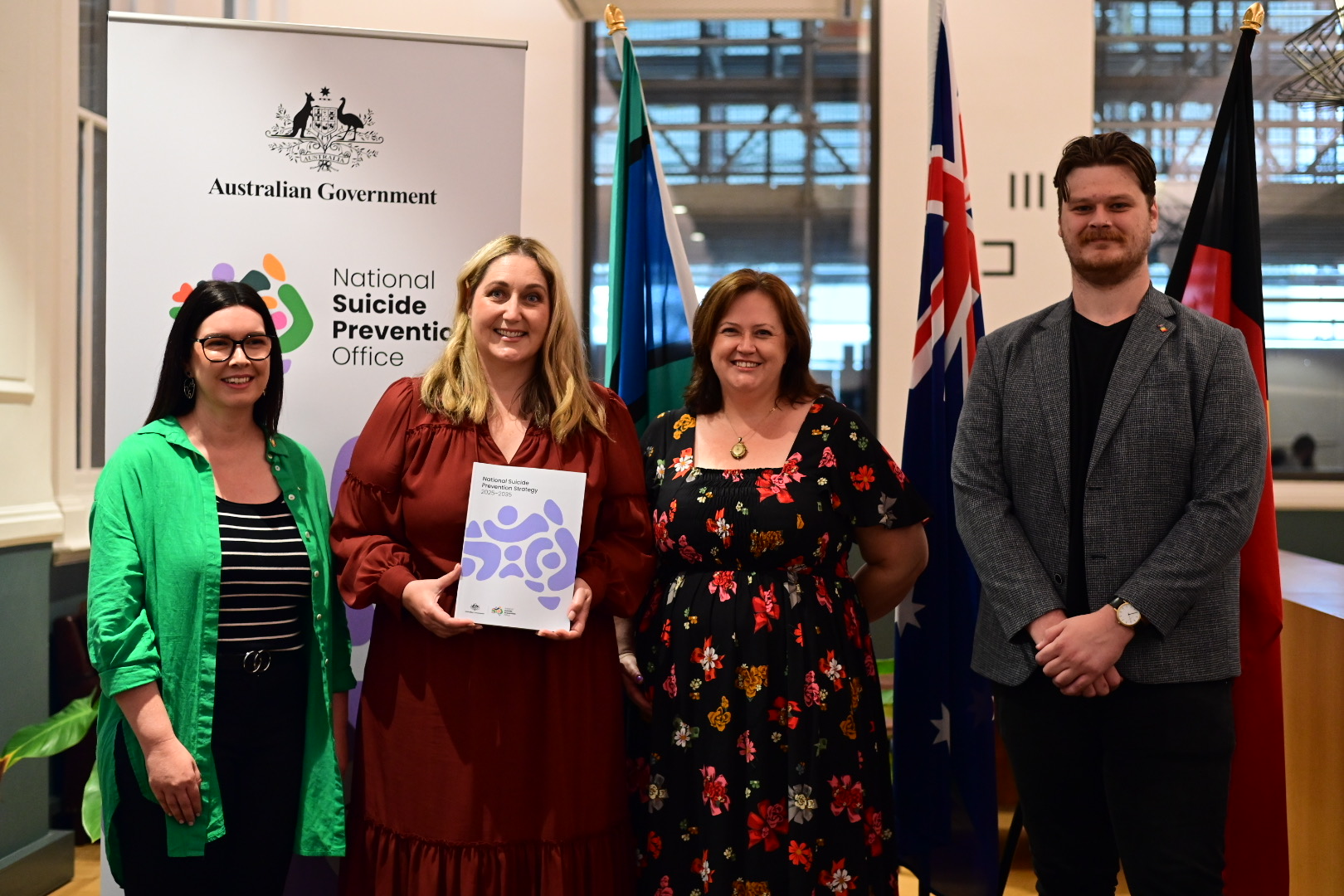 the Hon. Emma McBride holds the National Suicide Prevention Strategy alongside Lived Epxerience Partnership Group Members, (LtoR) Amy Bertakis, Jo Riley and Chritopher Trupp 